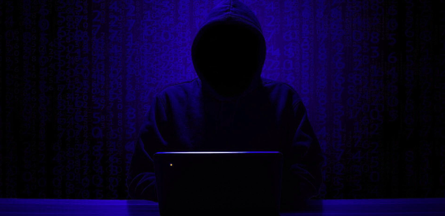 Hacker in dark room with code floating behind them