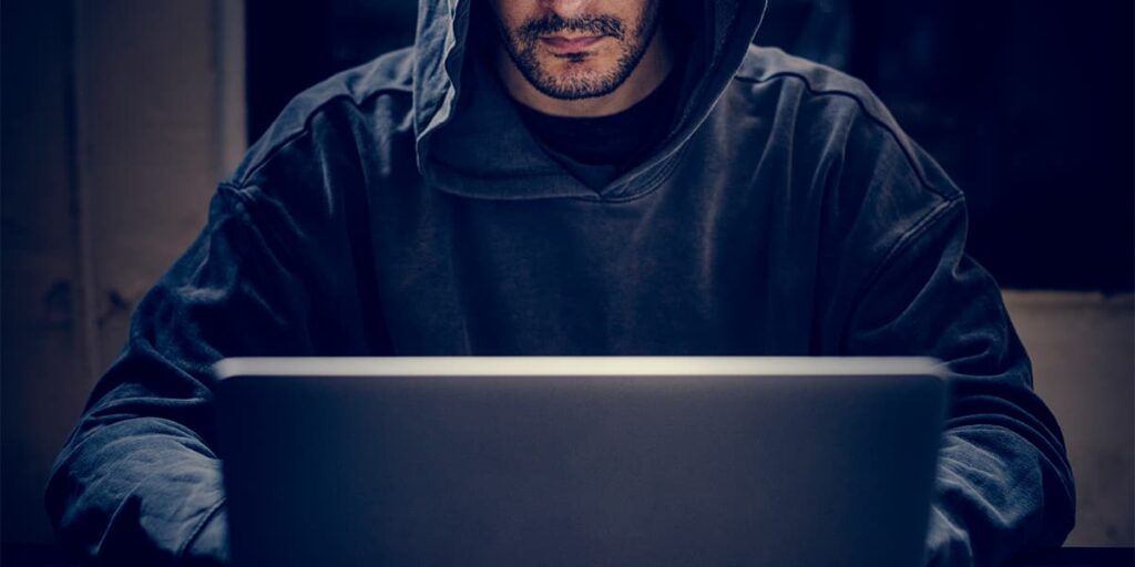 Hooded cybercriminal at a computer