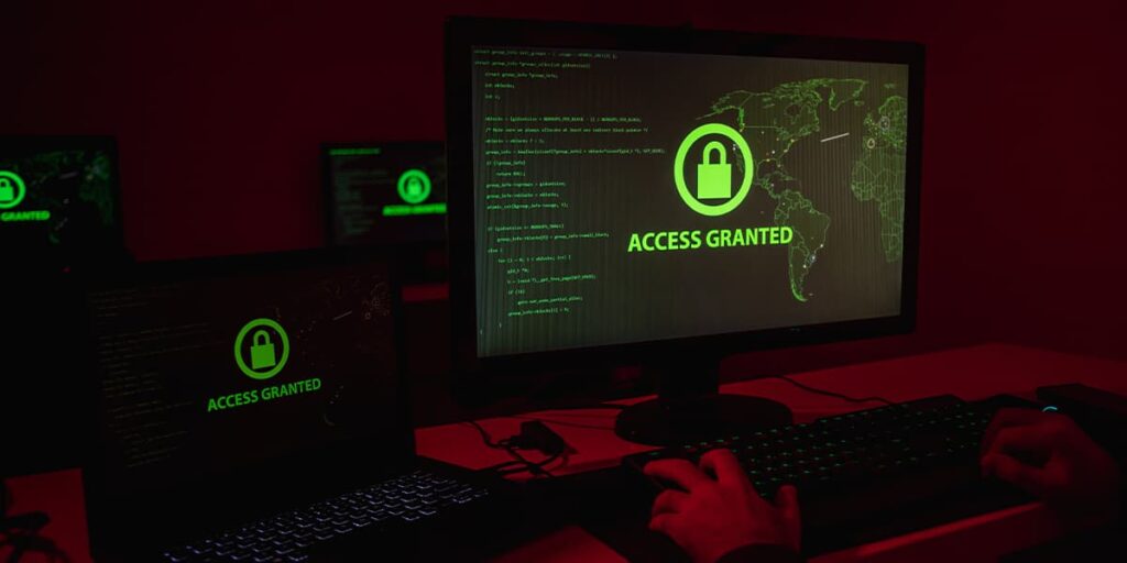 cybercriminal in red-lit room using compromised credentials to log into a system