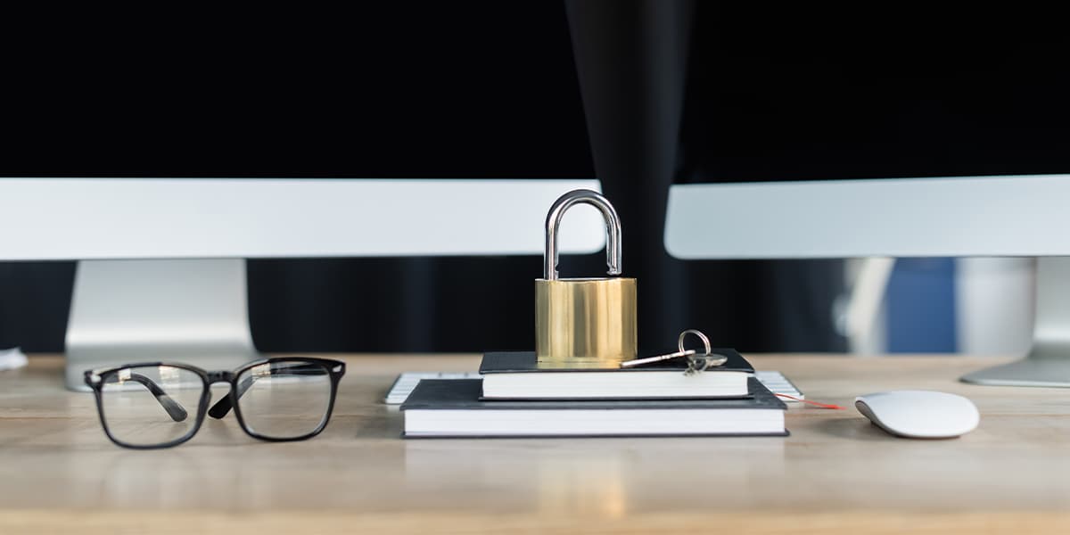 Padlock on notebooks near eyeglasses and computers on table in office