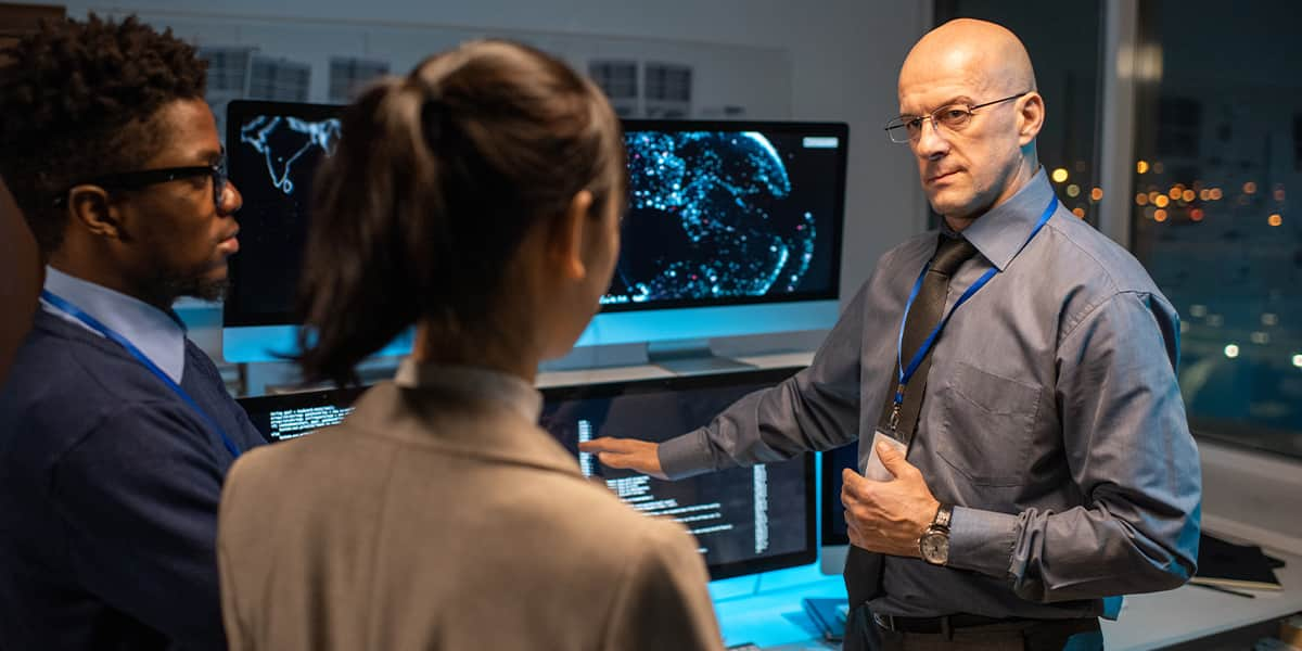 A bald person in a collared shirt trains younger colleagues