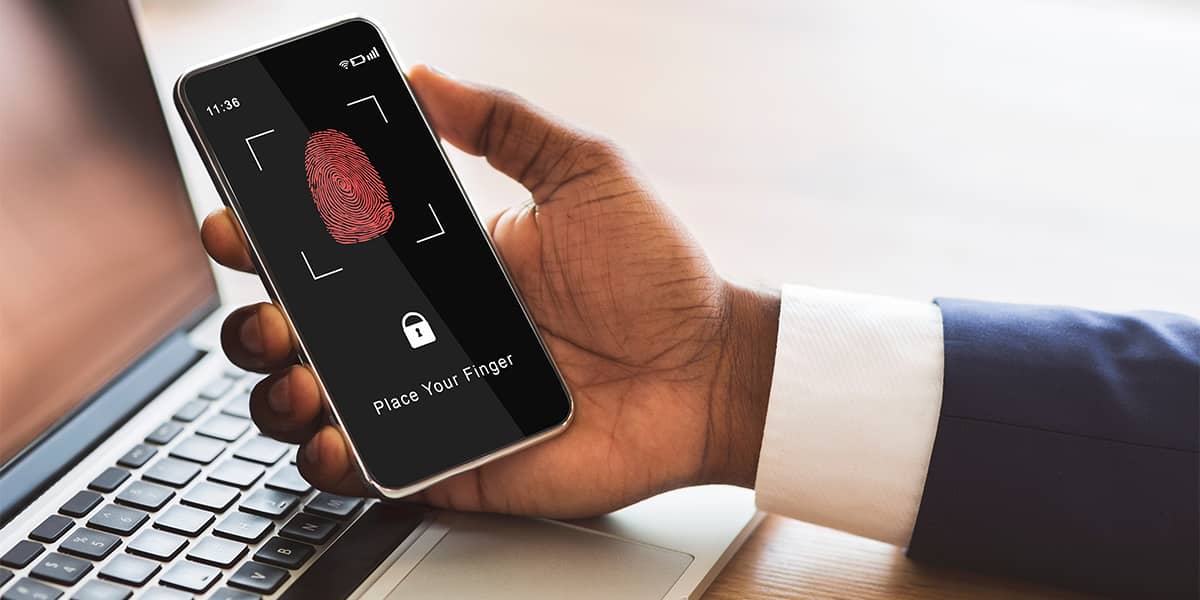 A person in a suit holds a smart phone with a fingerprint scanner