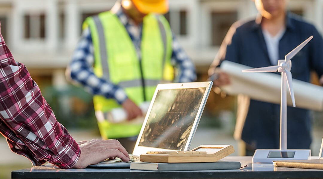 engineers discussing a solar energy project with a small solar panel model on the table, a laptop